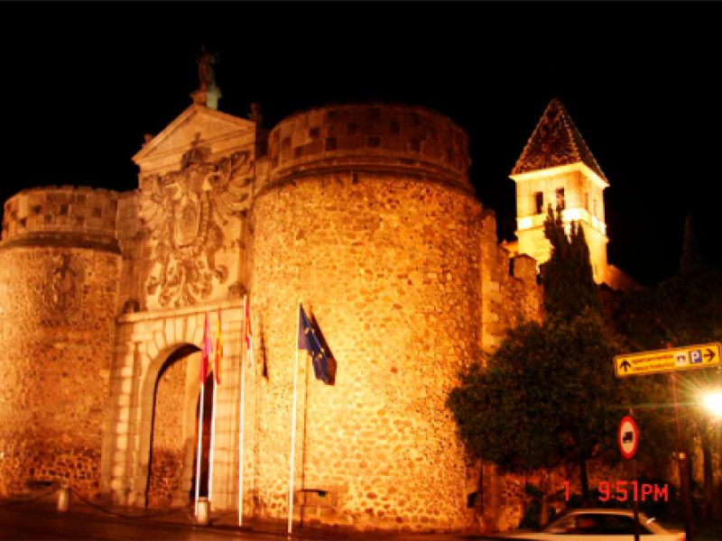Vista lateral desde la calle de la Purrta Bisagra iluminada artísticamente en Toledo