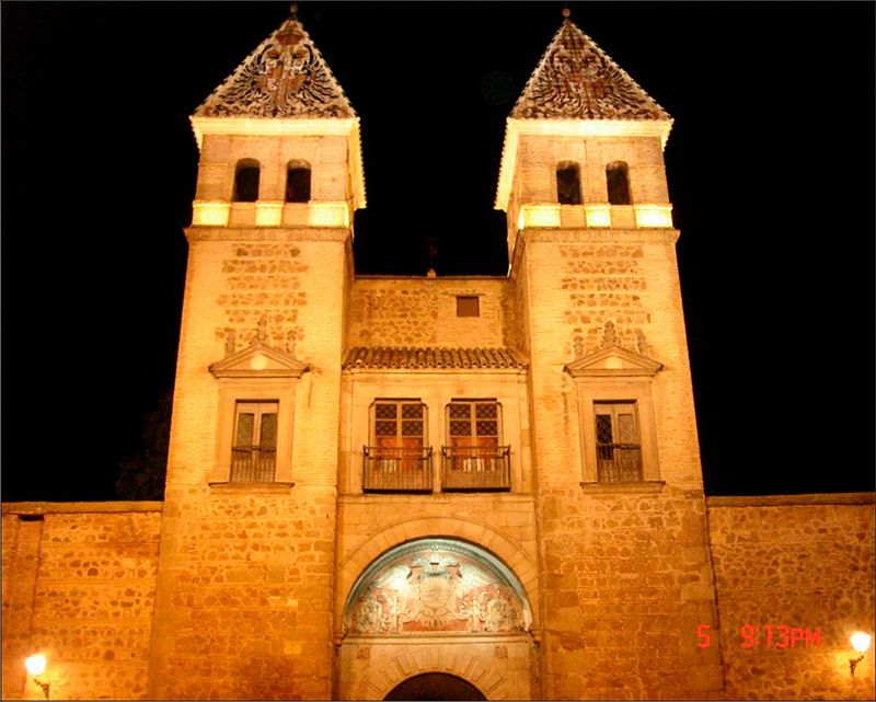 Vista frontal de la Puerta Bisagra en Toledo iluminada artísticamente