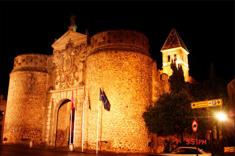 Vista lateral desde la calle de la Purrta Bisagra iluminada artísticamente en Toledo