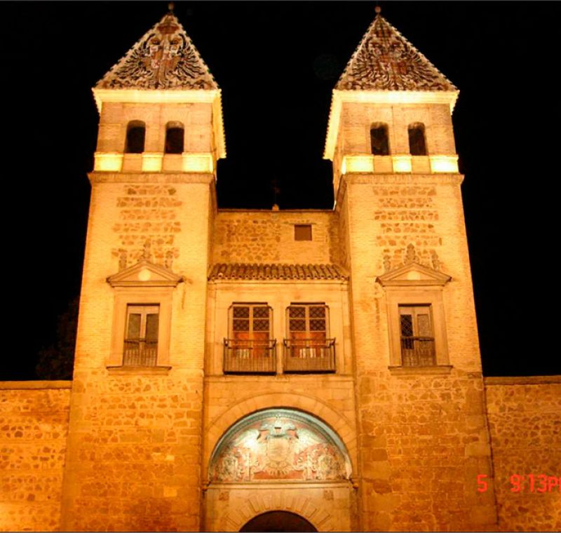 Vista frontal de la Puerta Bisagra en Toledo iluminada artísticamente